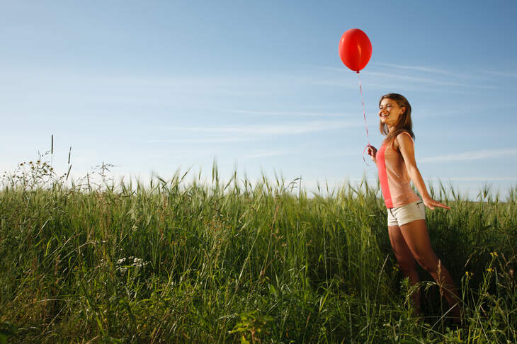 Girl with the red balloon stands on the field